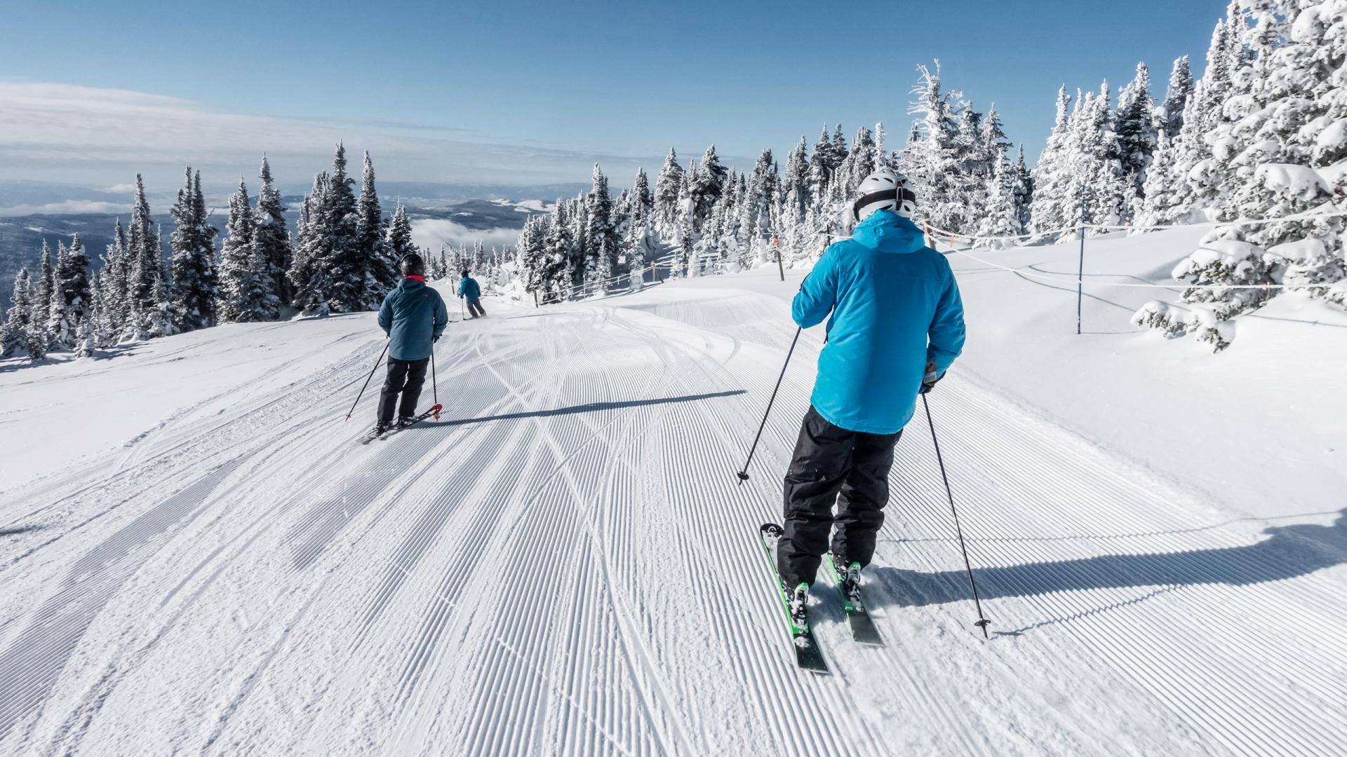 Trois personnes sont en train de descendre une piste à ski