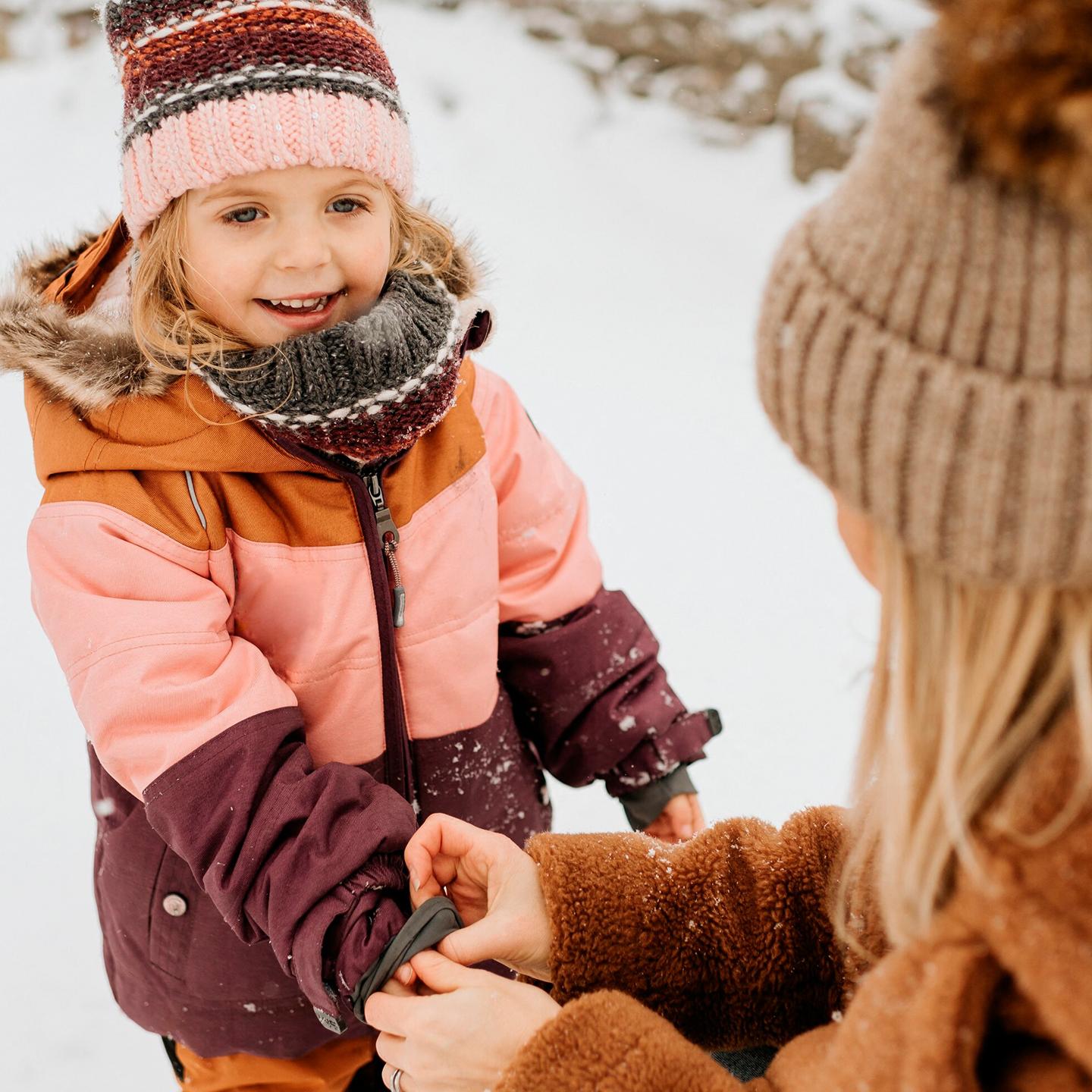 Une fillette et sa mère jouent dans la neige