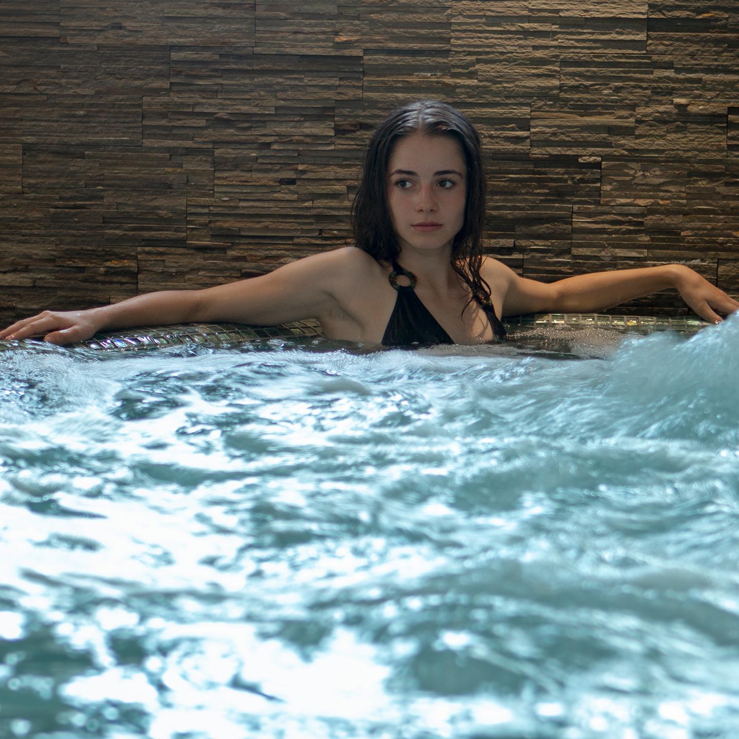 Une femme se détend dans un bain bouillonnant du Spa Montagnes du Monde®