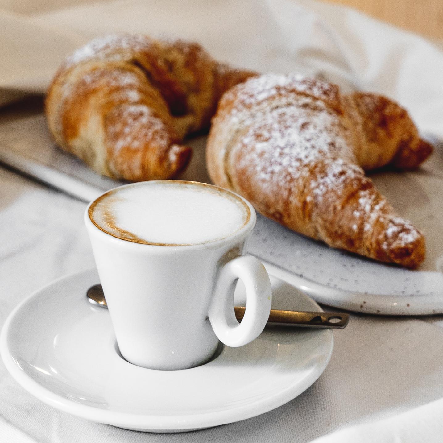 Un café est des croissants sont posés sur une table