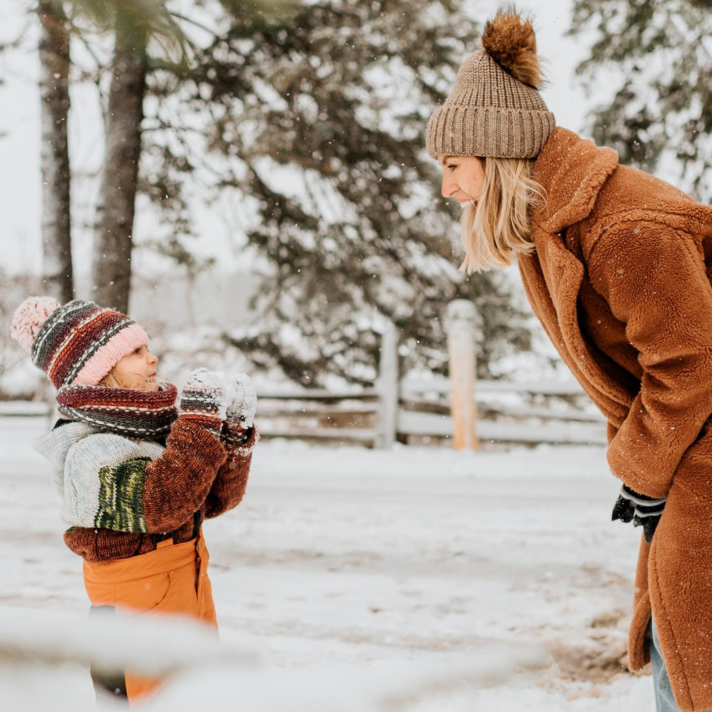 Un petit garçon joue et rigole avec sa maman dans la neige - Enfants et famille