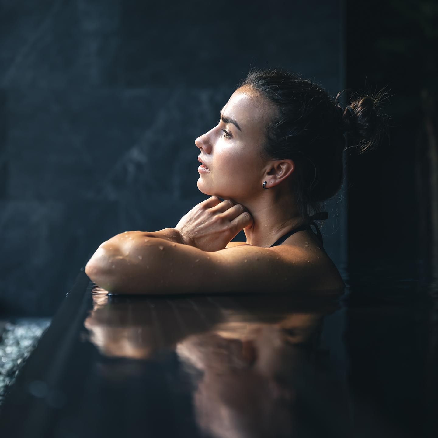 Une femme est en train d regarder par la fenêtre de la piscine du Spa Montagnes du Monde®