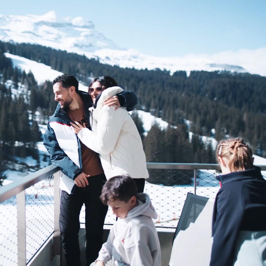Vacances à la montagne en hiver, une famille profite du soleil sur le balcon de l'hôtel & résidence Alhéna à Flaine