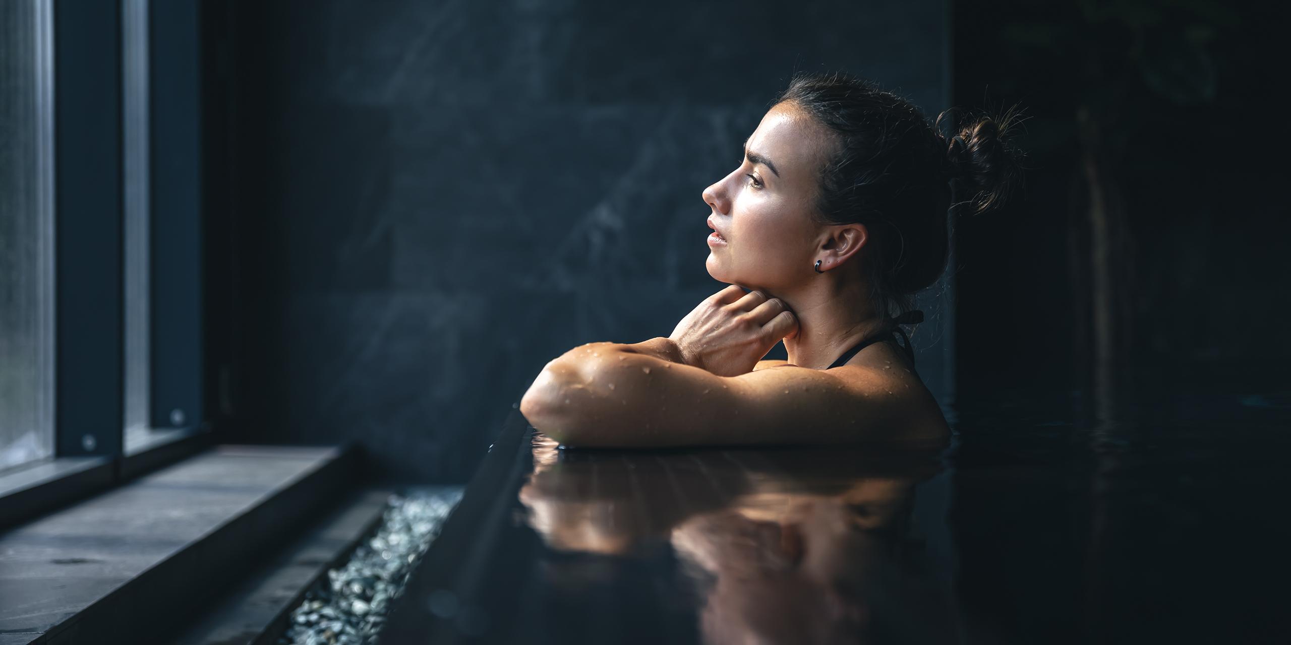 Une femme est en train d regarder par la fenêtre de la piscine du Spa Montagnes du Monde®