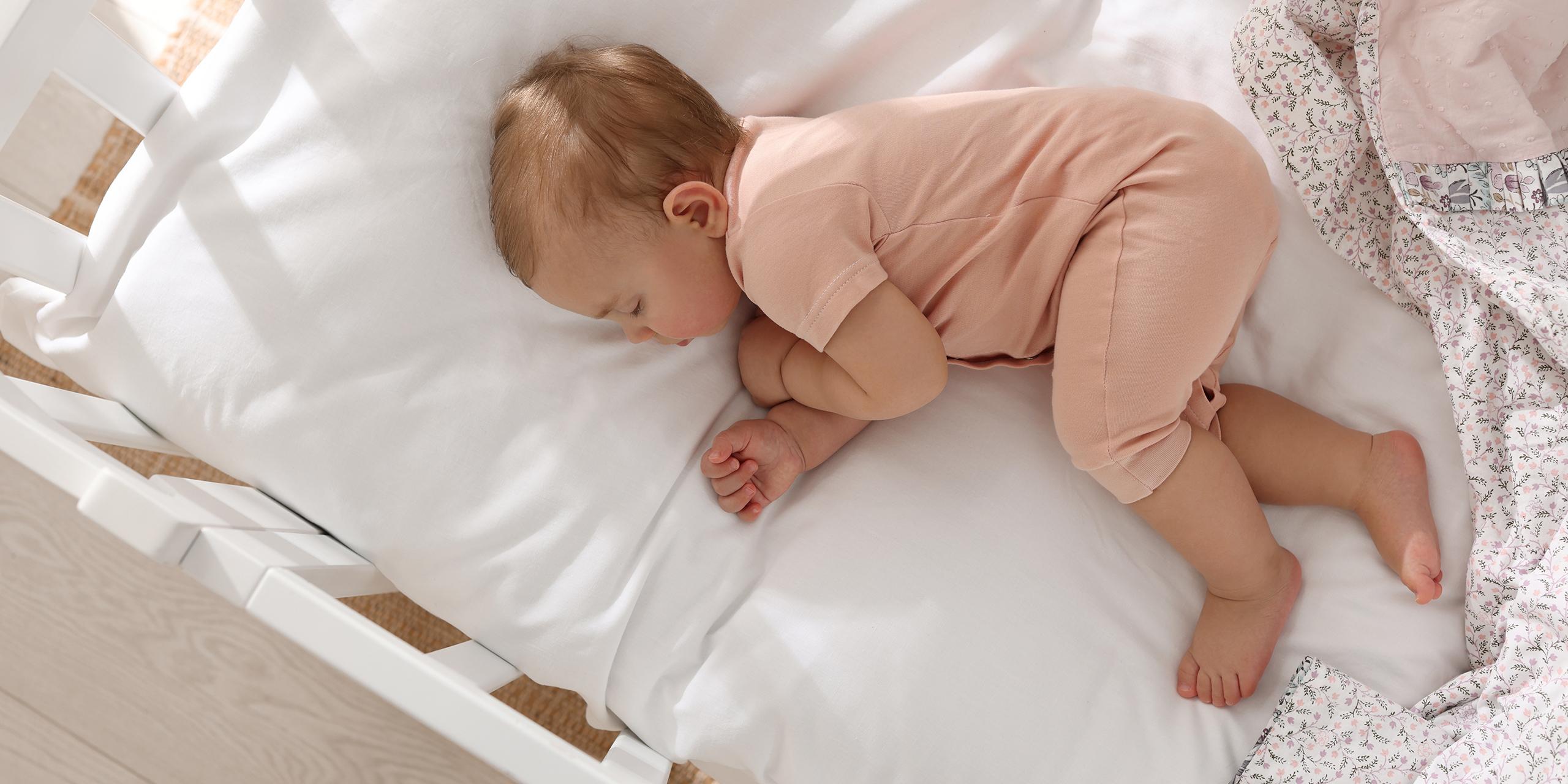 Un bébé dort dans son lit en bois