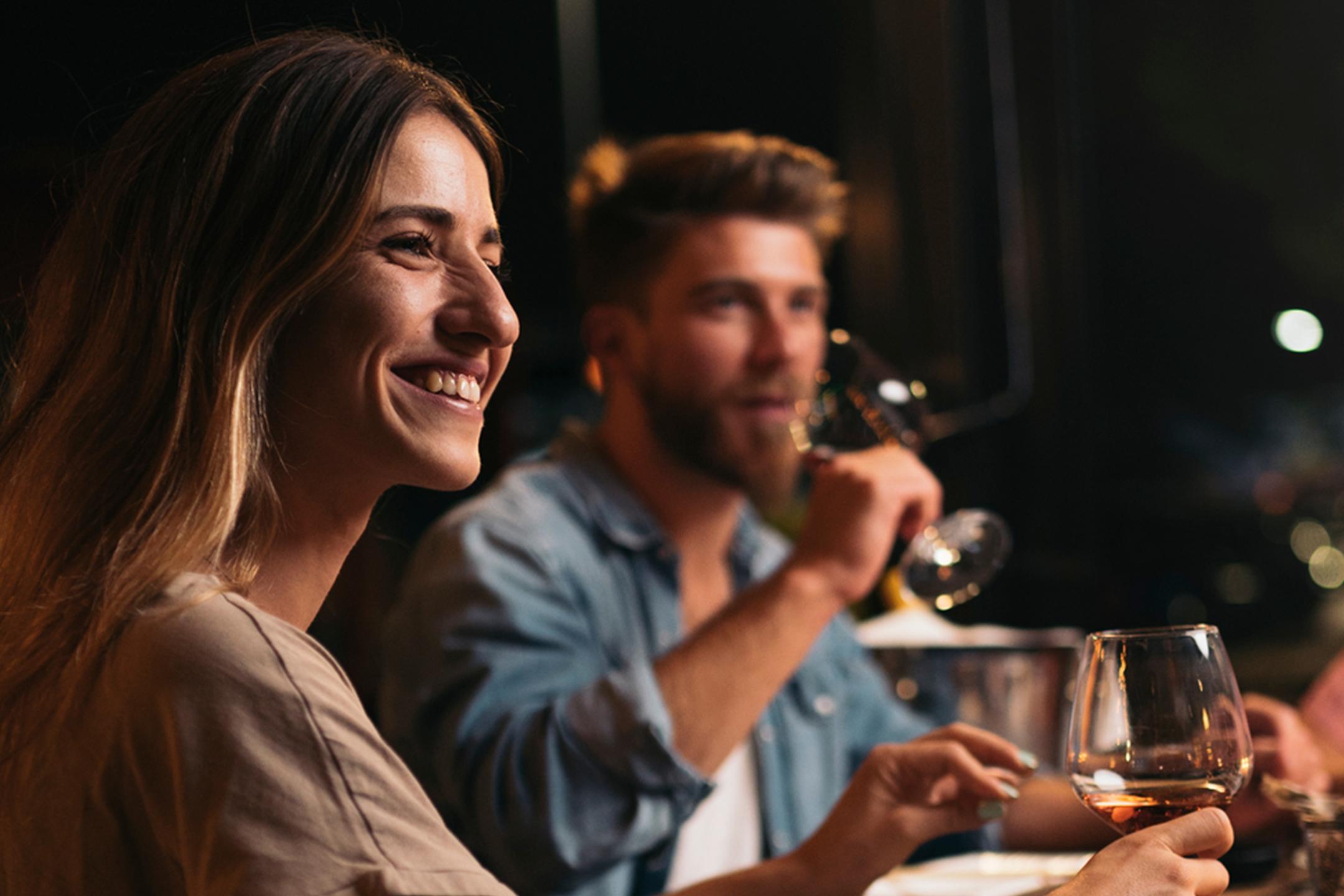 Un homme et une femme sont au restaurant avec un verre de vin à la main