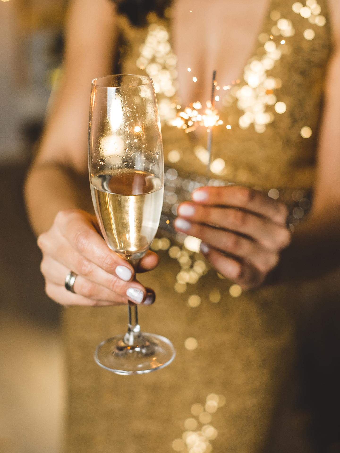 Une femme porte un verre de champagne à la main