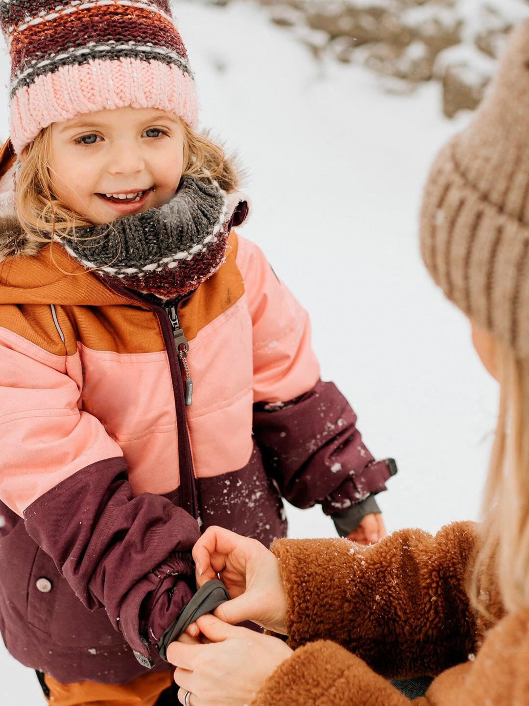 Une fillette et sa mère jouent dans la neige