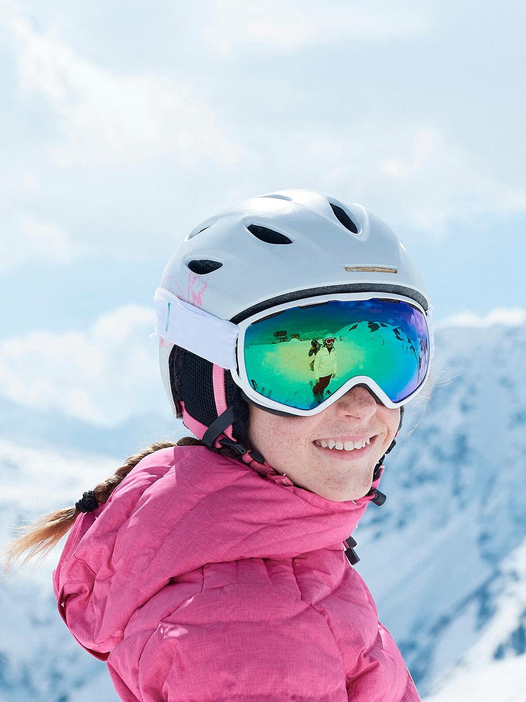 Une jeune fille regarde en souriant une autre personne sur une piste de ski