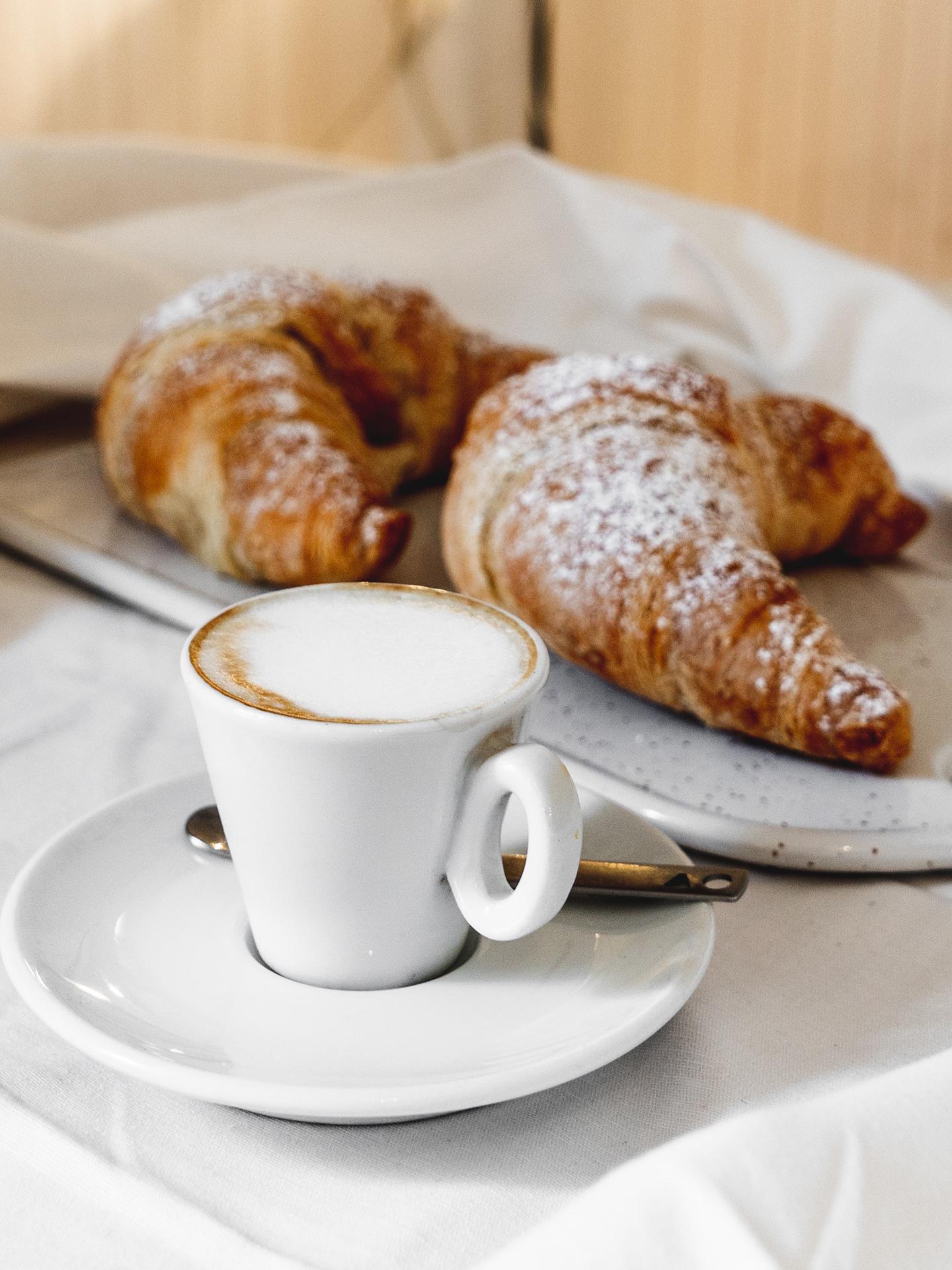 Un café est des croissants sont posés sur une table