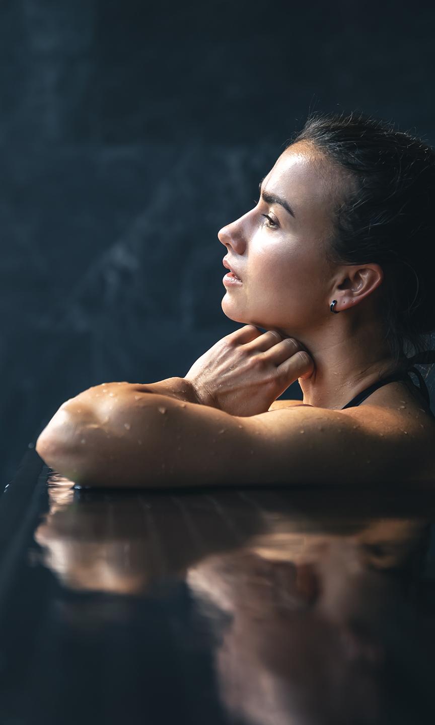 Une femme est en train d regarder par la fenêtre de la piscine du Spa Montagnes du Monde®