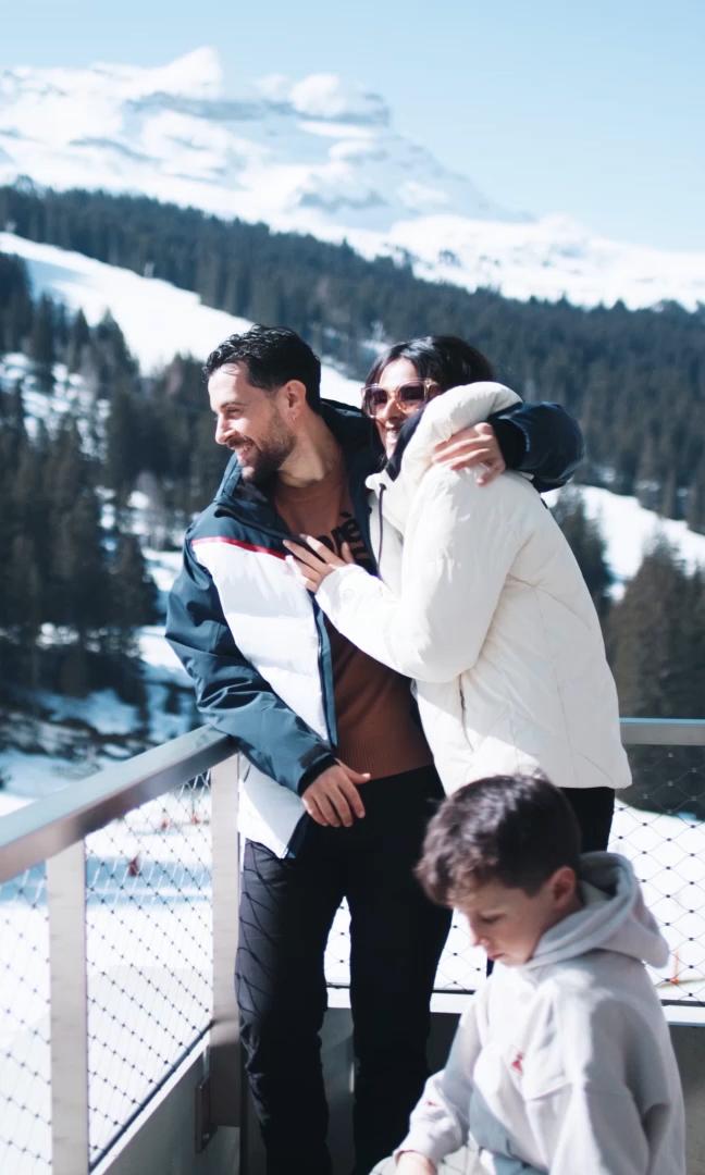 Vacances à la montagne en hiver, une famille profite du soleil sur le balcon de l'hôtel & résidence Alhéna à Flaine