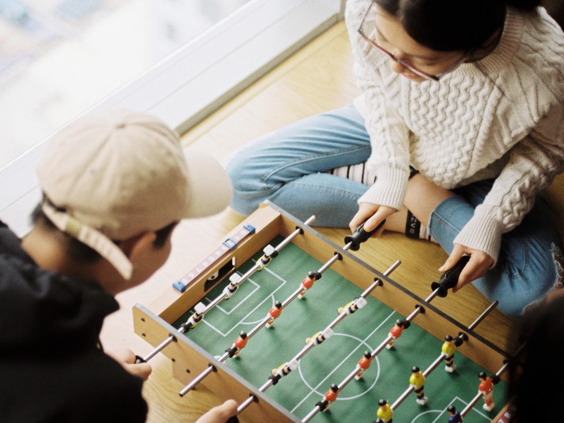 Deux jeunes sont en train de jouer à un mini babyfoot