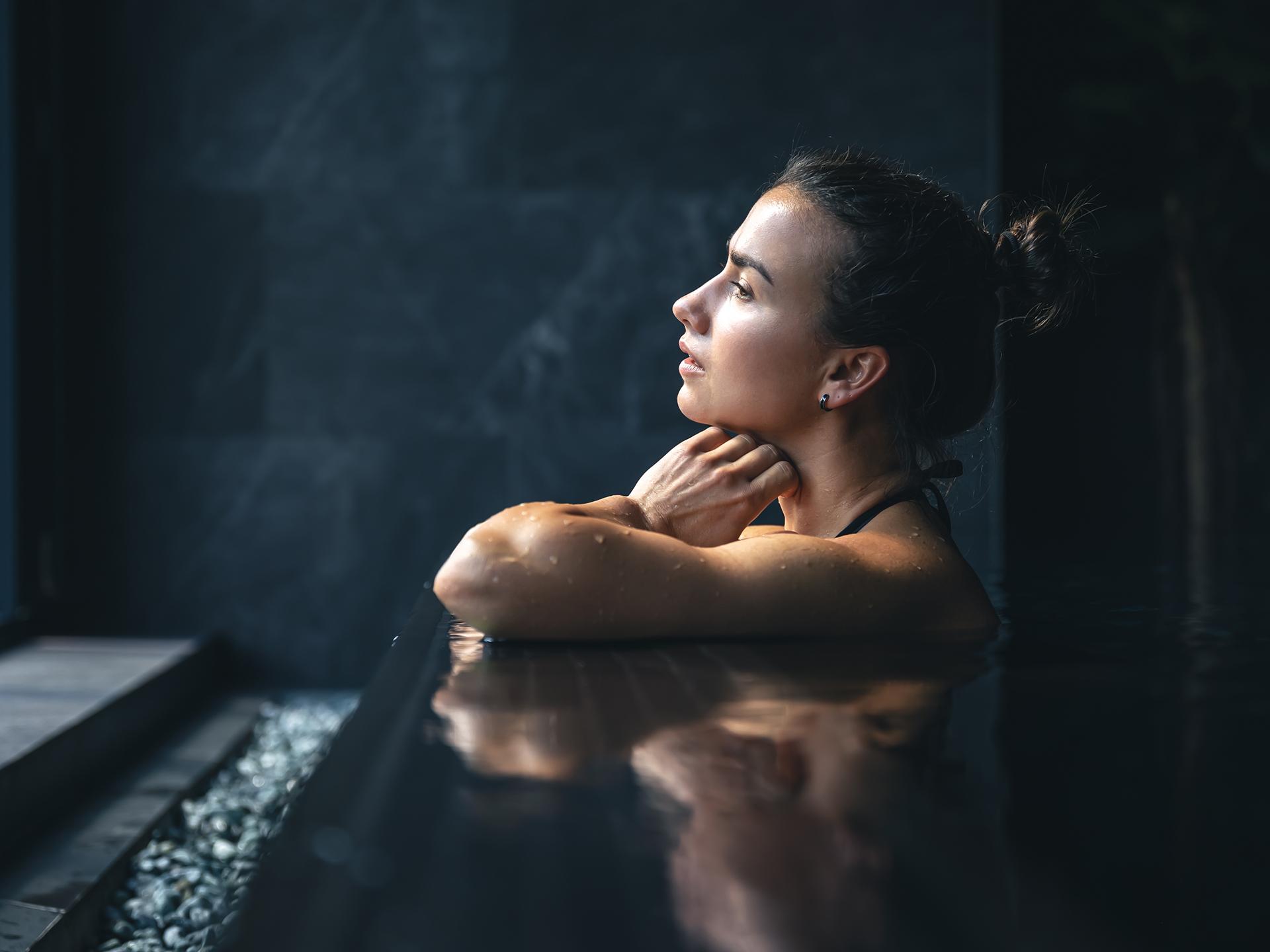 Une femme est en train d regarder par la fenêtre de la piscine du Spa Montagnes du Monde®