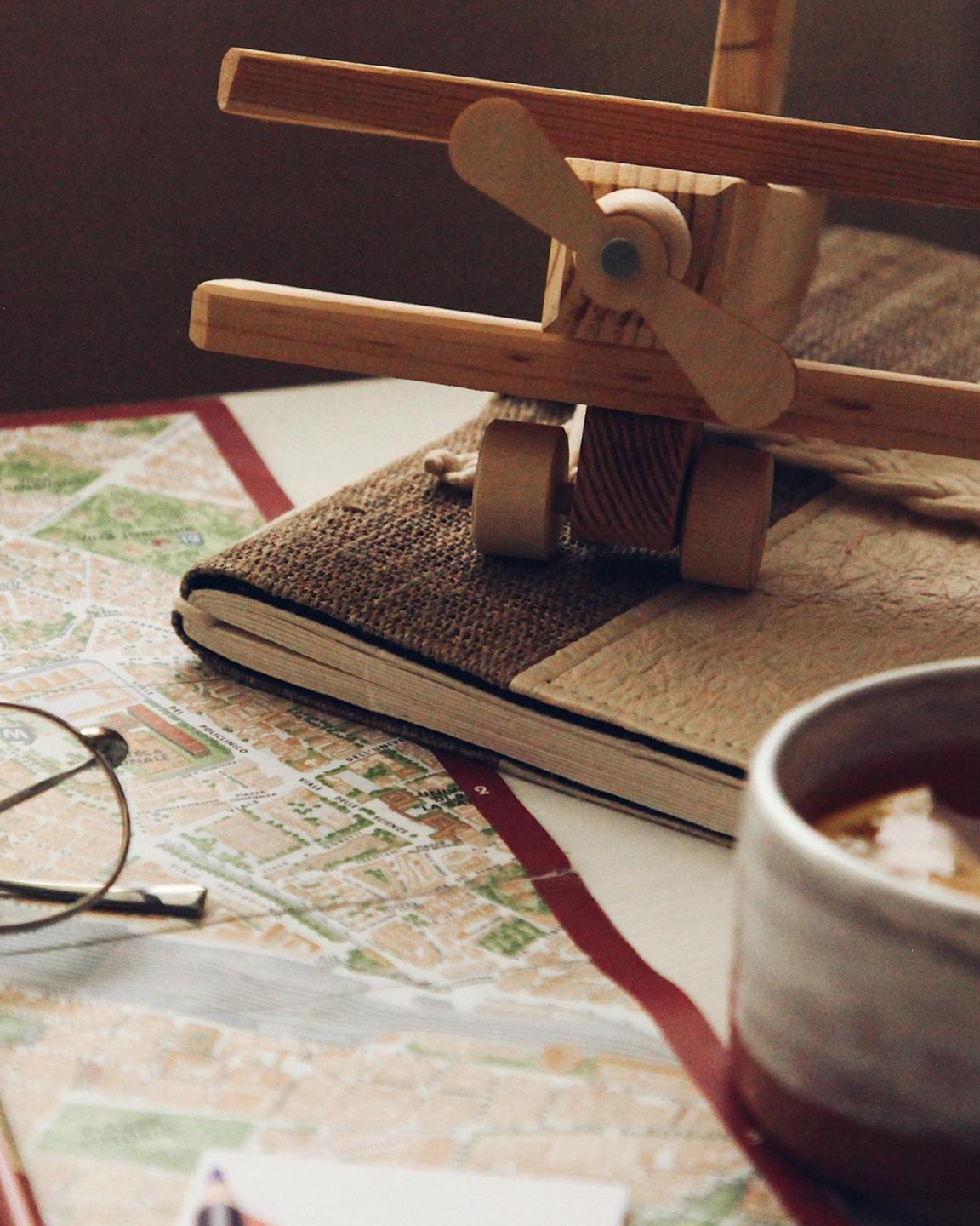 Un avion en bois, une carte, des lunette et des crayons de couleur sont posés sur une table