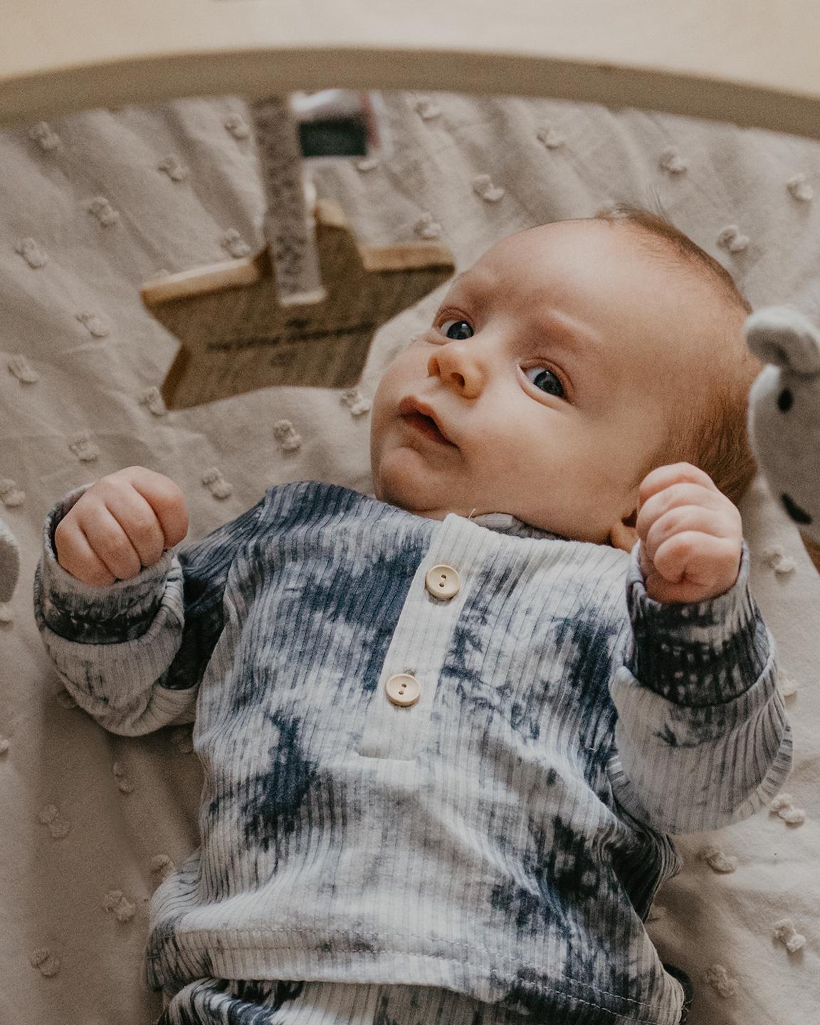 Un bébé est en train de jouer allongé sur un coussin