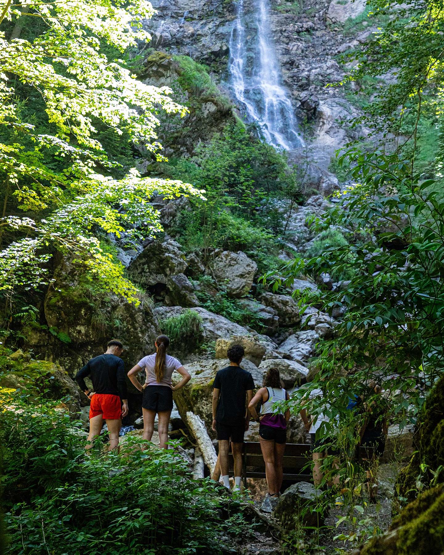 Groupe de sportifs faisant une pause devant une cascade de montagne dans le cadre du programme MGM Sérénité