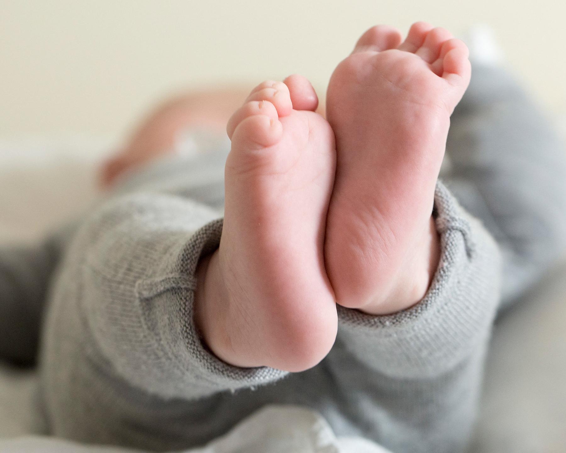 Un bébé est allongé sur un matelas, ses pieds sont au premier plan