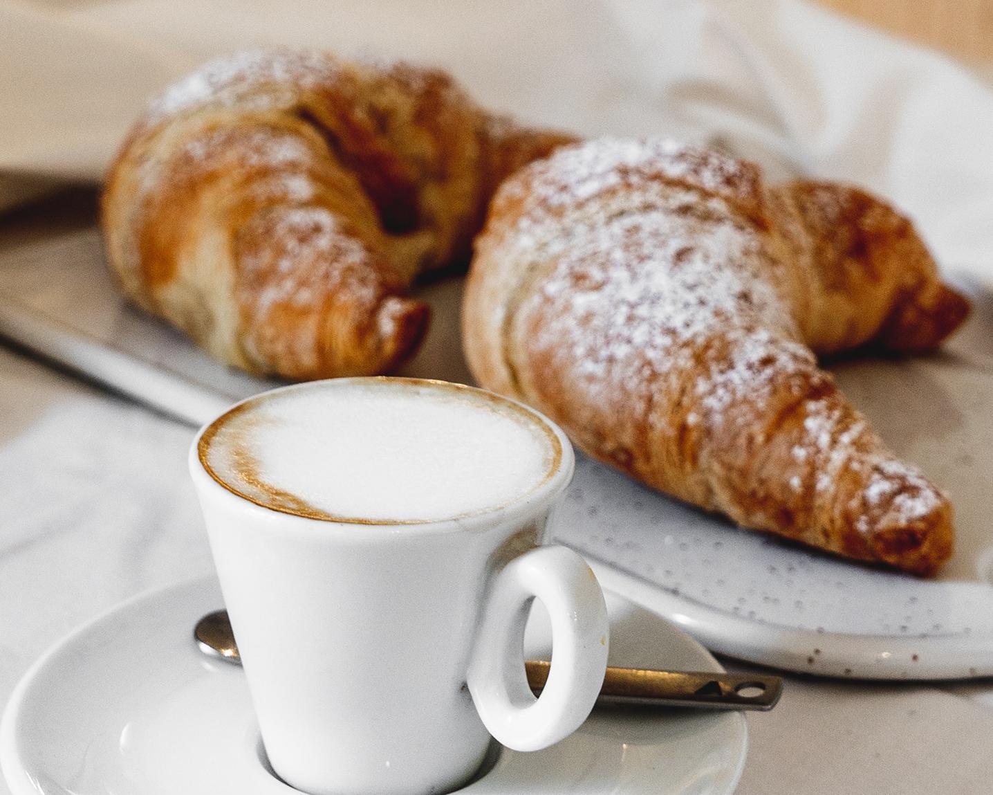 Un café est des croissants sont posés sur une table