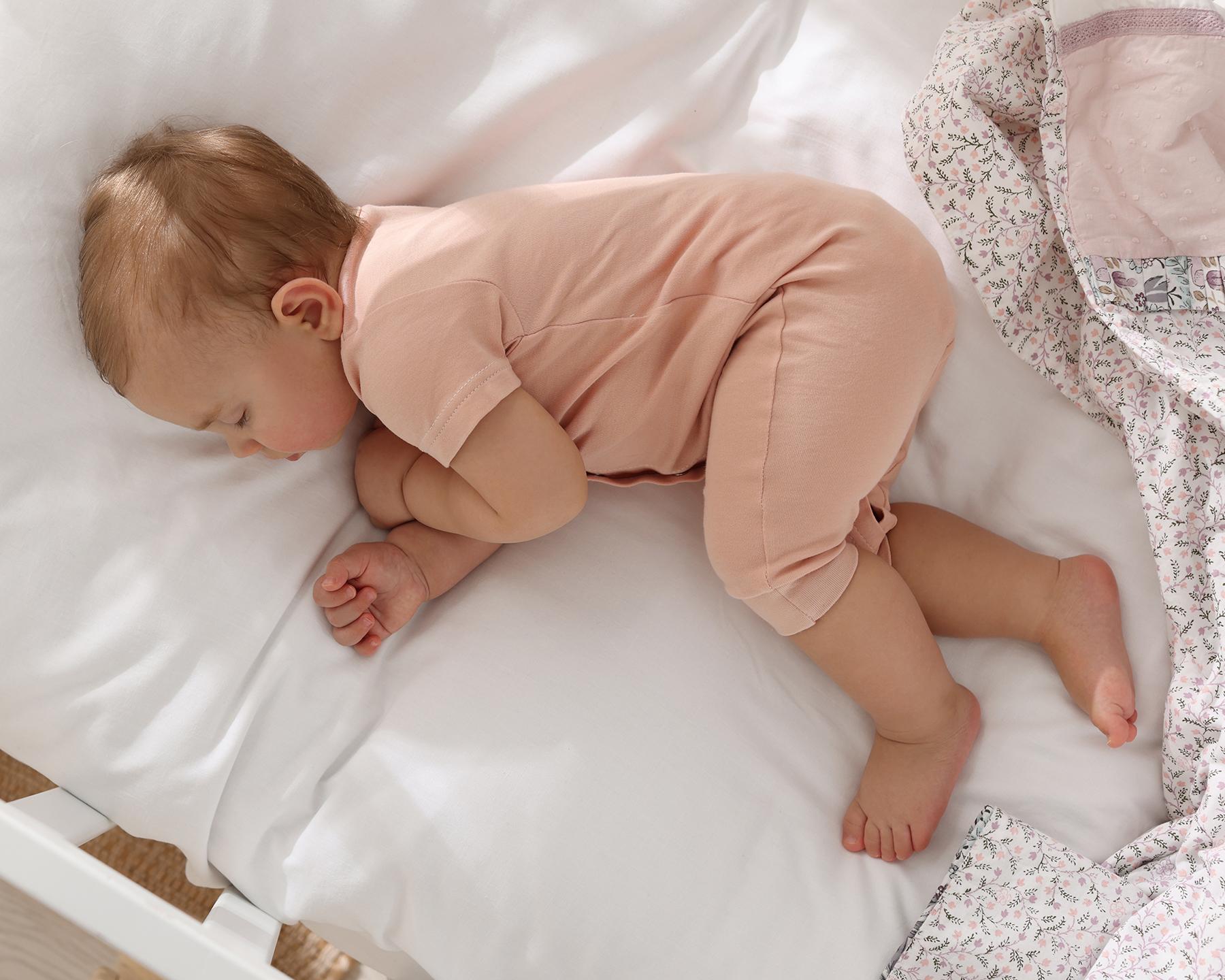 Un bébé dort dans son lit en bois