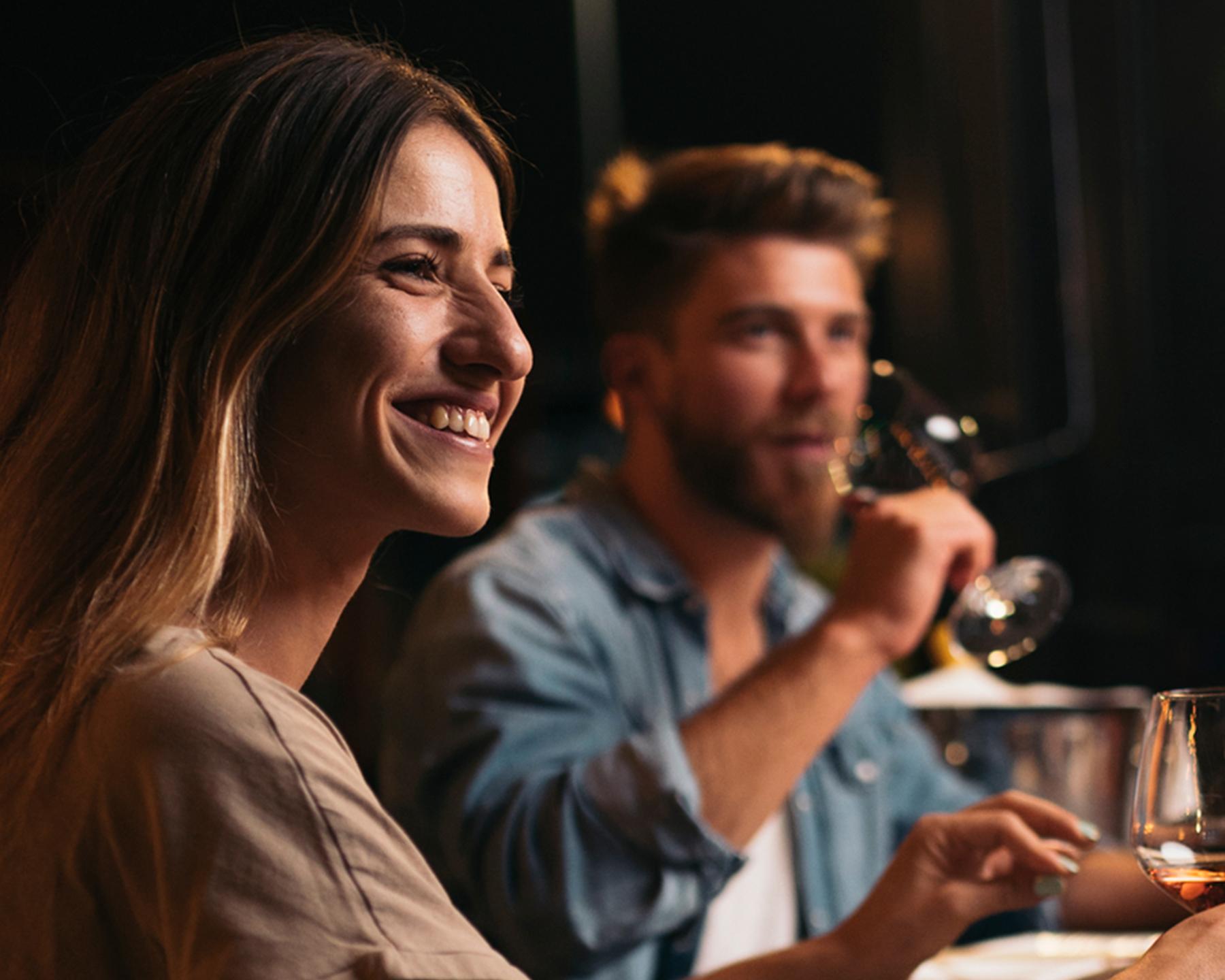 Un homme et une femme sont au restaurant avec un verre de vin à la main