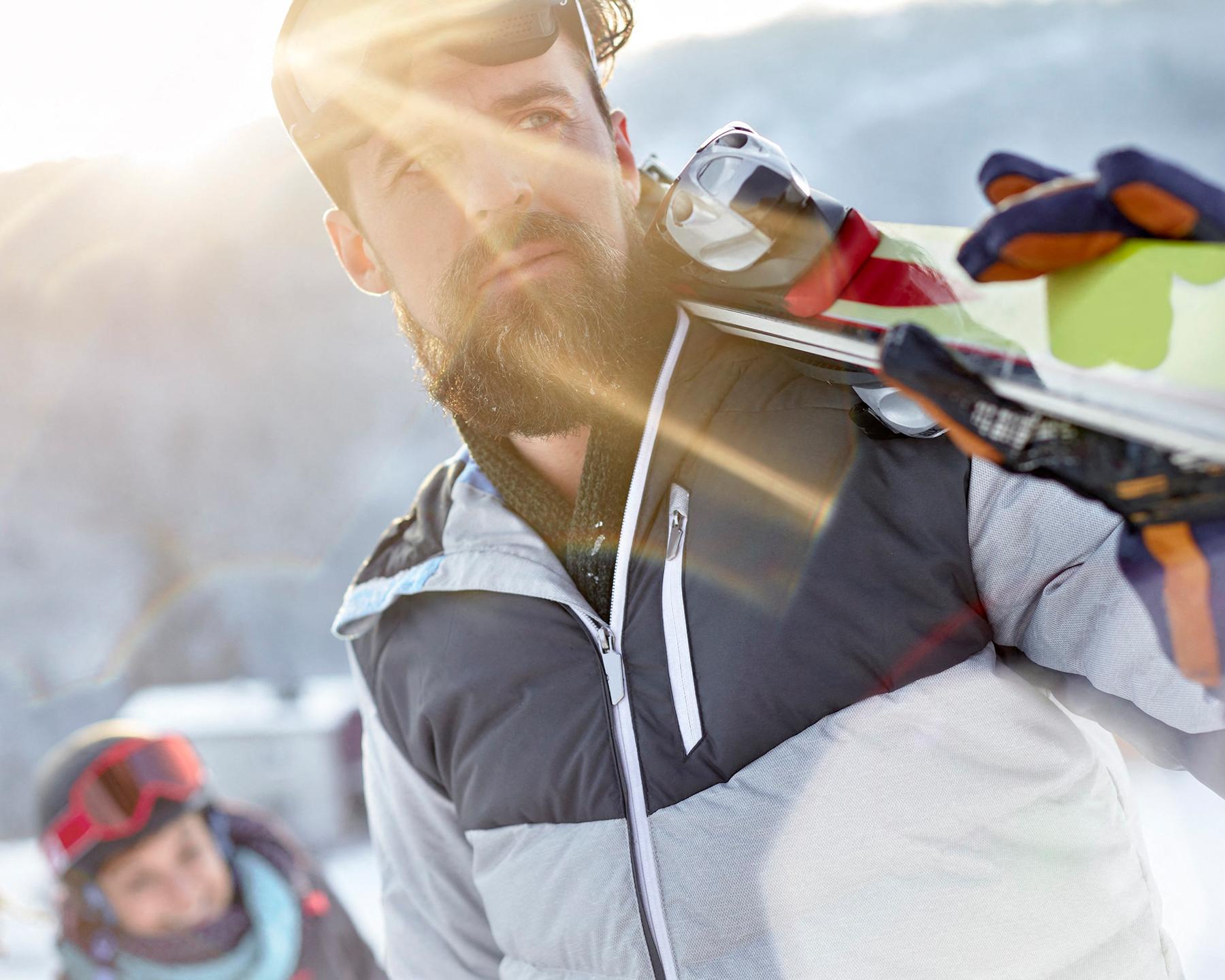 Les services MGM - Vacances à la montagne en hiver - Homme qui porte des skis 