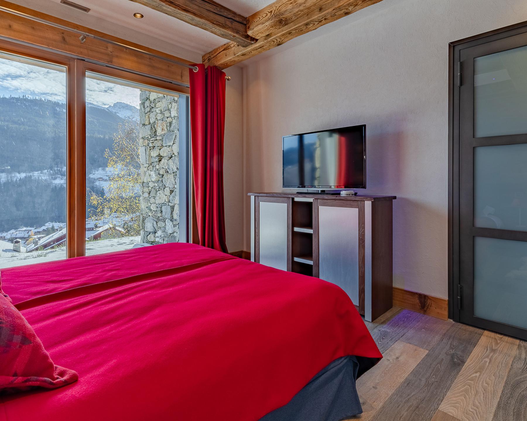 Chambre aux tons rouges avec télévision du Chalet Apsara à Méribel