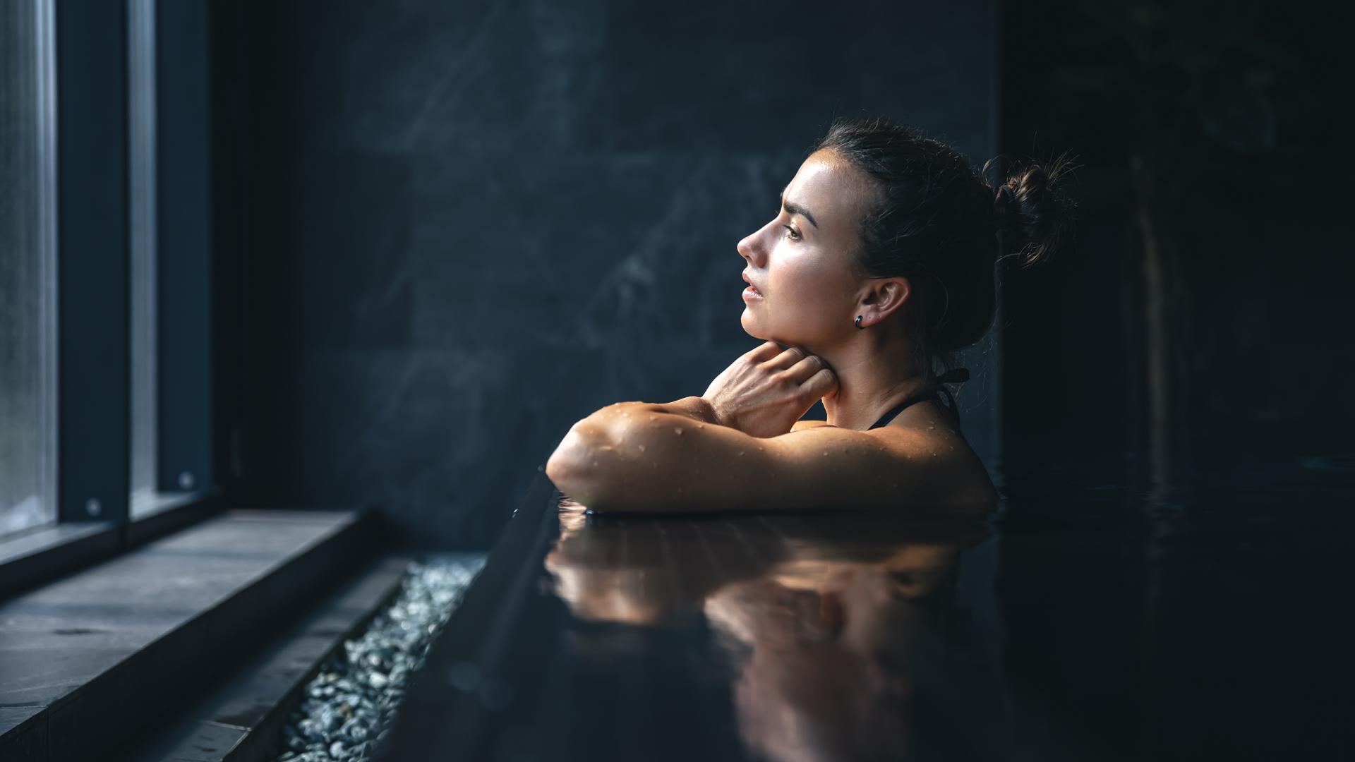 Une femme est en train d regarder par la fenêtre de la piscine du Spa Montagnes du Monde®