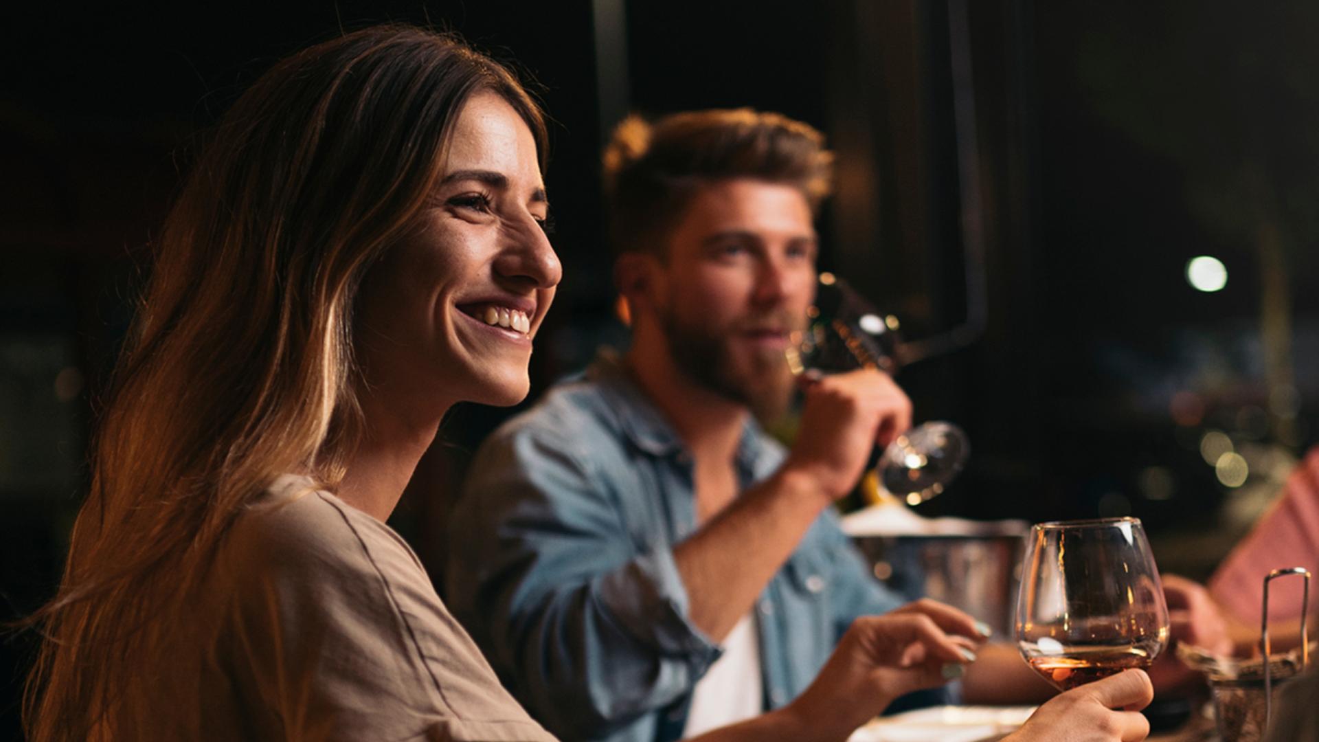 Un homme et une femme sont au restaurant avec un verre de vin à la main