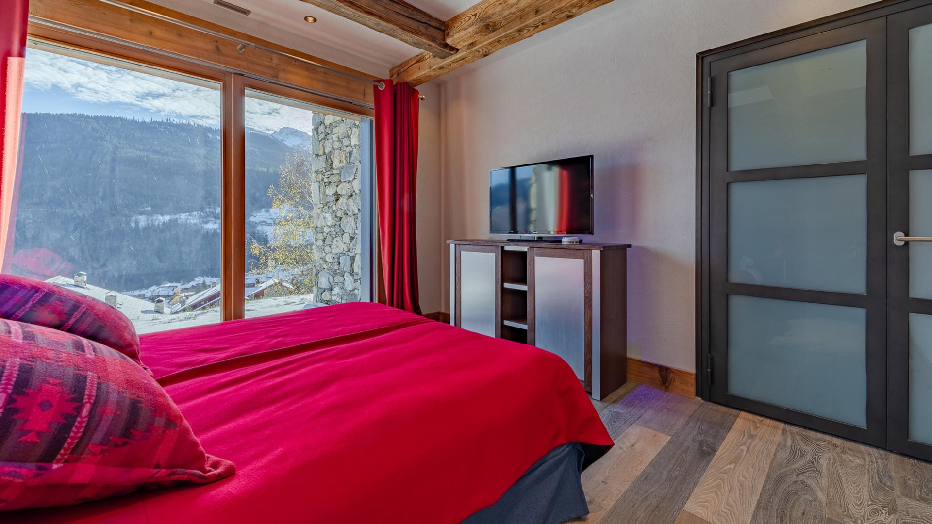 Chambre aux tons rouges avec télévision du Chalet Apsara à Méribel