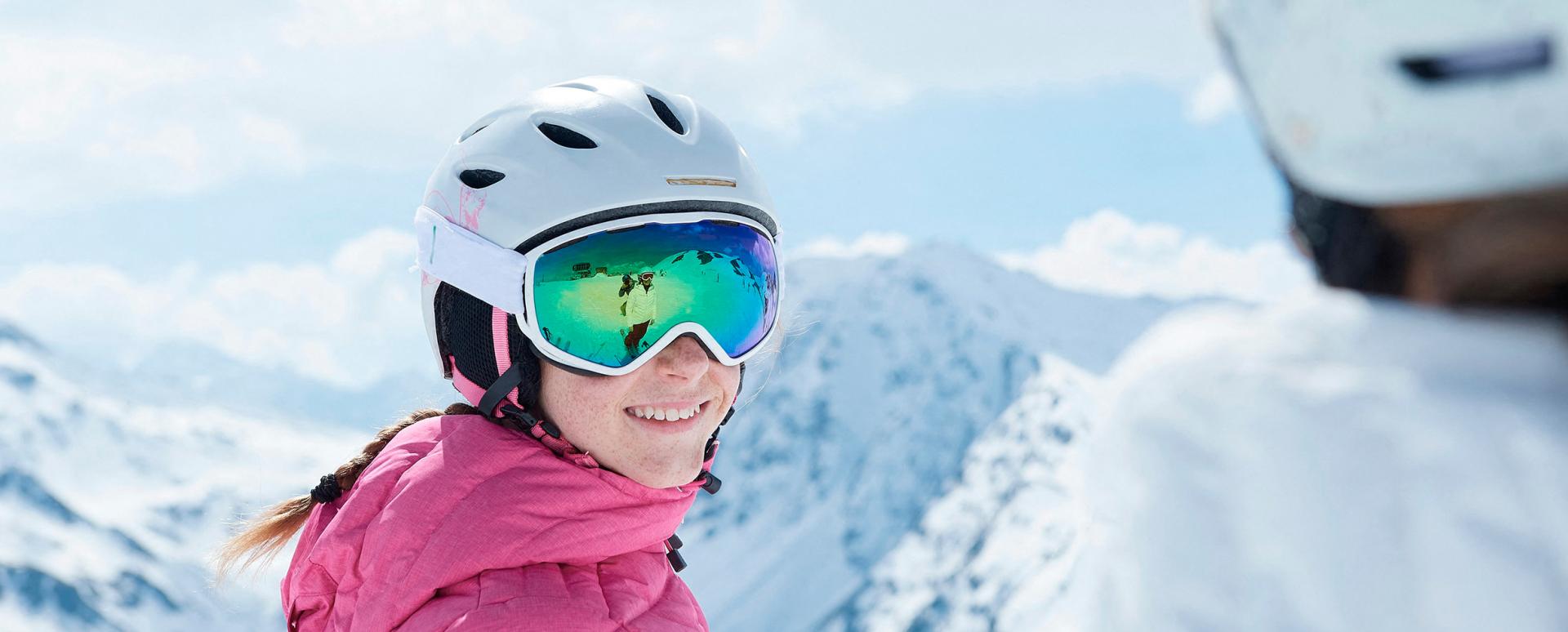 Une jeune fille regarde en souriant une autre personne sur une piste de ski