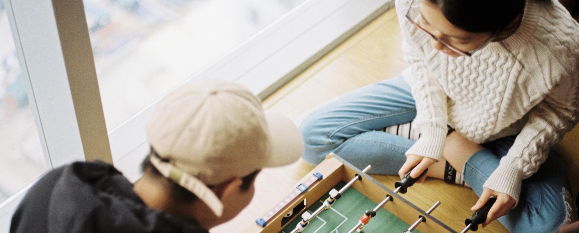 Deux jeunes sont en train de jouer à un mini babyfoot