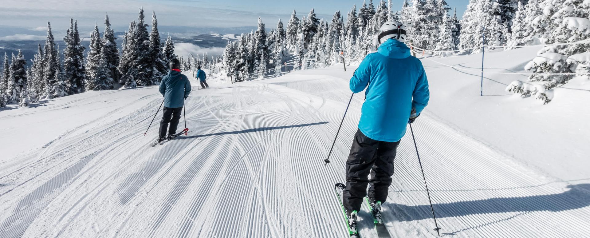 Trois personnes sont en train de descendre une piste à ski