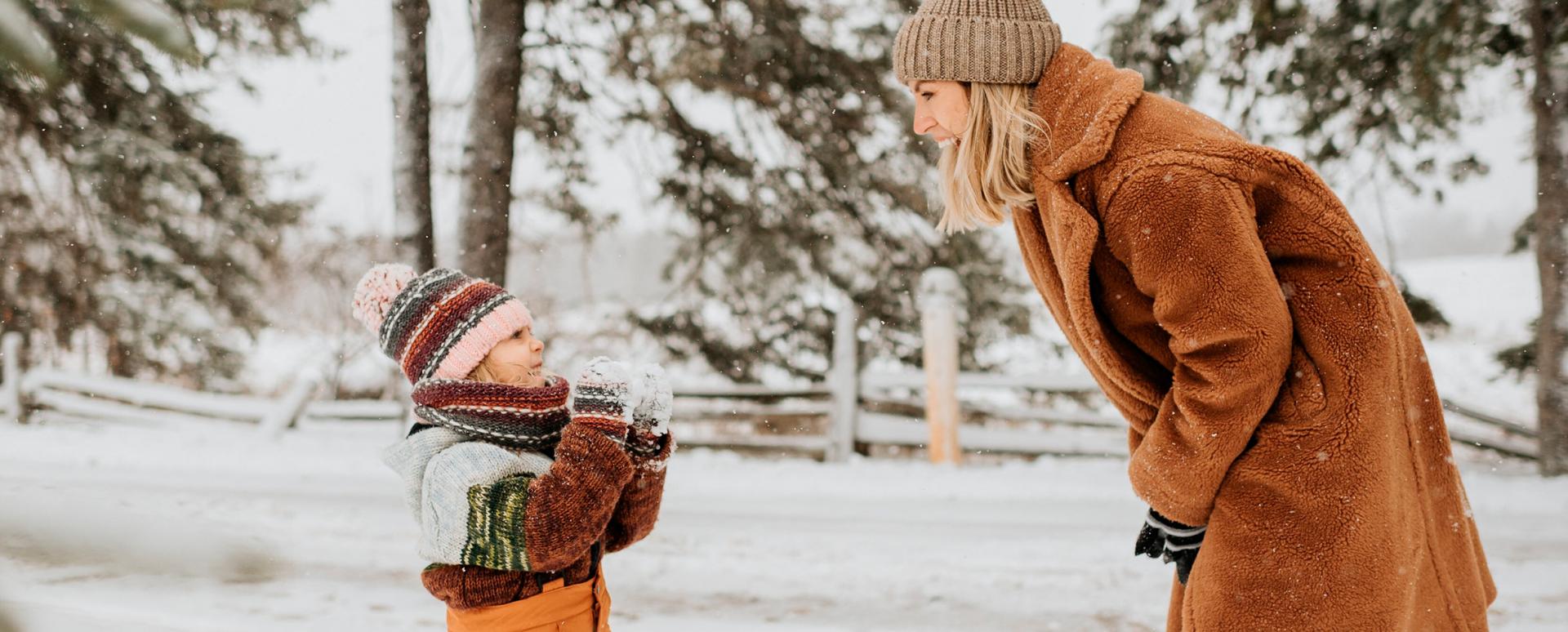 Un petit garçon joue et rigole avec sa maman dans la neige - Enfants et famille