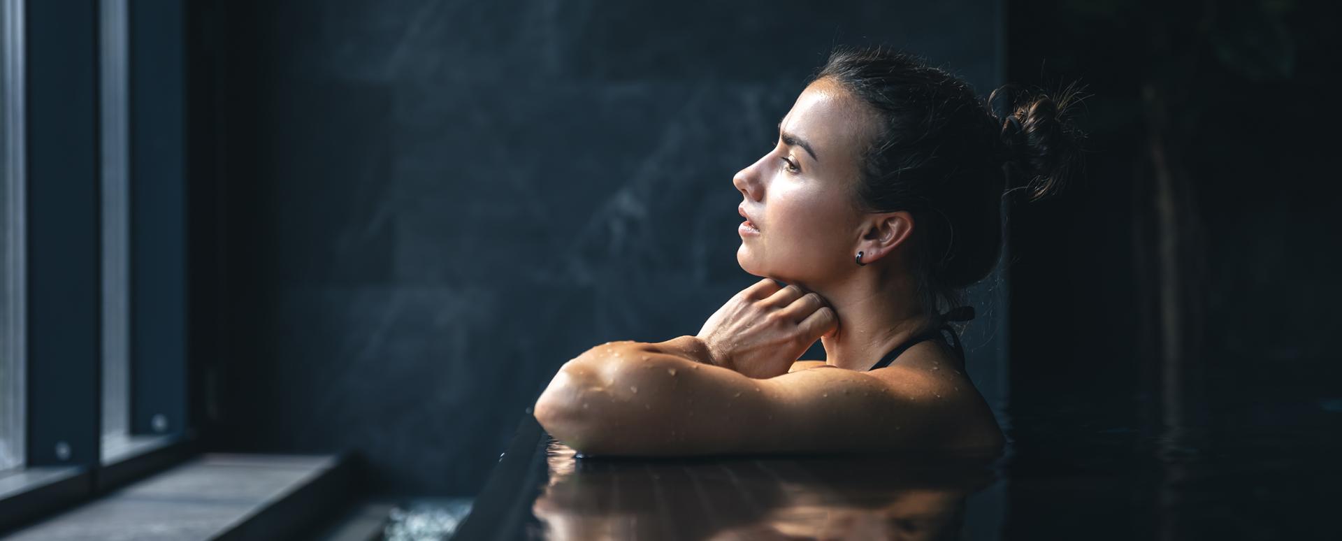 Une femme est en train d regarder par la fenêtre de la piscine du Spa Montagnes du Monde®