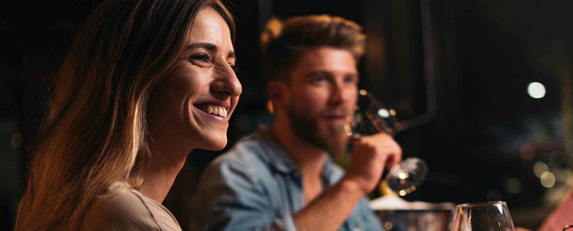 Un homme et une femme sont au restaurant avec un verre de vin à la main