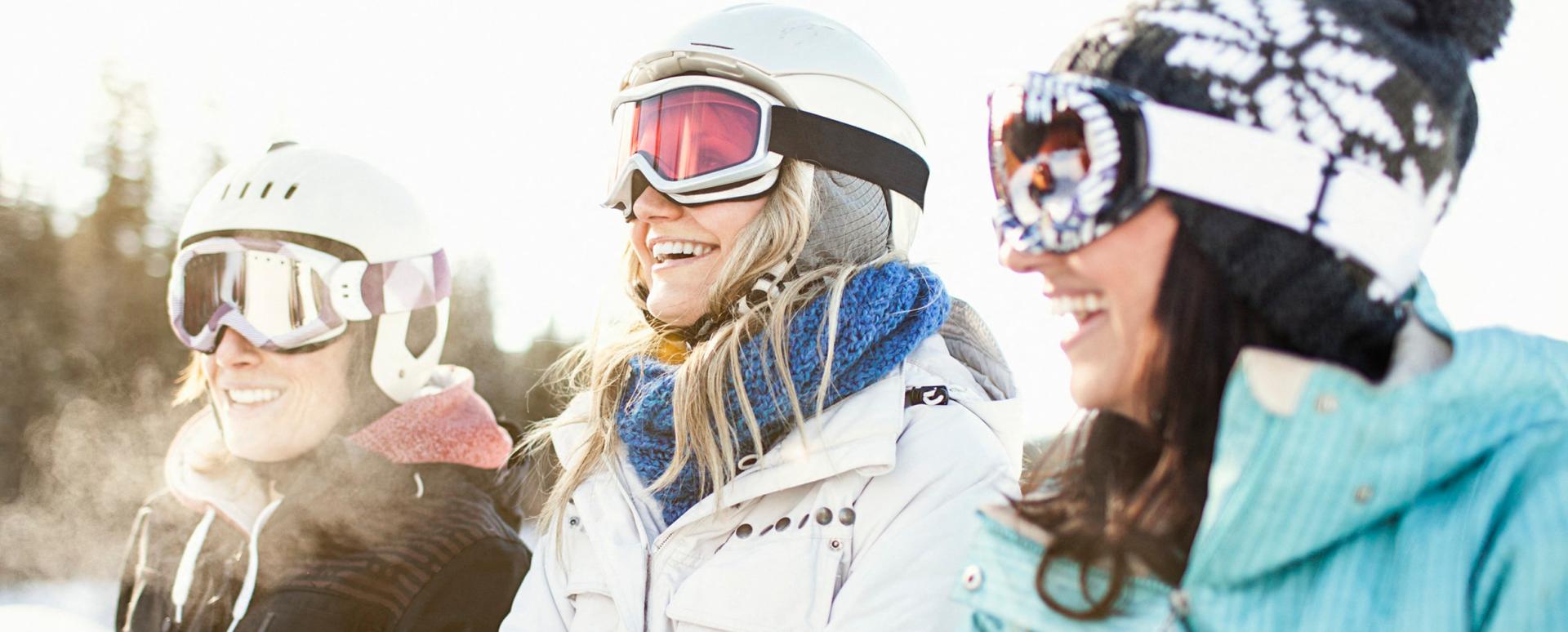 3 femmes sont assises dans la neige avec leurs équipements pour le ski