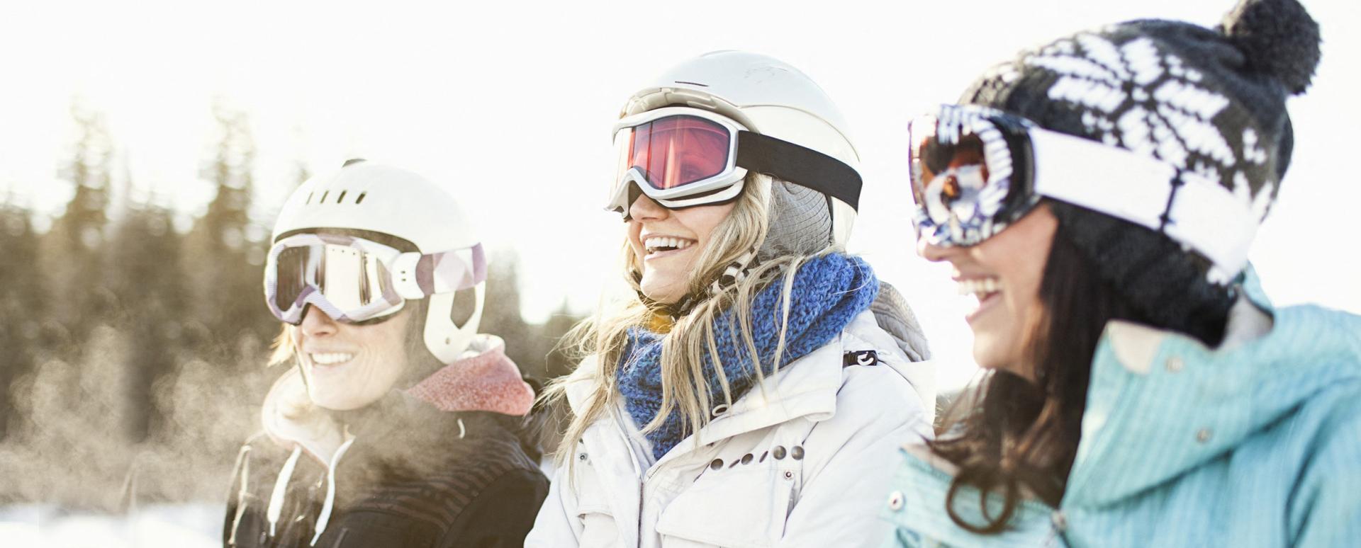 3 femmes sont assises dans la neige avec leurs équipements pour le ski